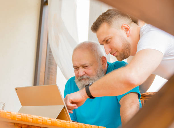 息子と父親はタブレットのラップトップを使用しています - retirement grandfather senior adult child ストックフォトと画像