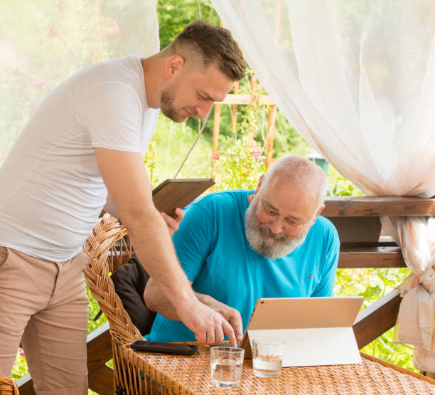 息子と父親はタブレットのラップトップを使用しています - retirement grandfather senior adult child ストックフォトと画像