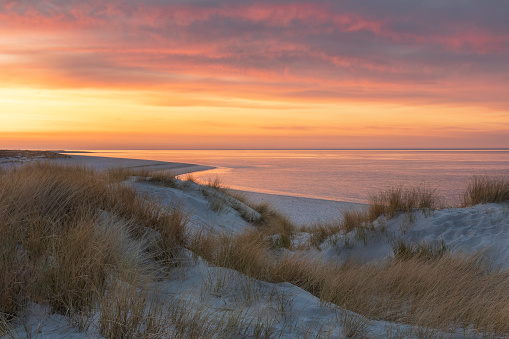 Idyllic beach of Sylt island directly after sunset with a dramatic sky and a free view up to the horizon