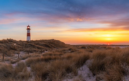 Tall dunes with dune grass and a wide beach below. Photographed at sunset on the island of Texel in The Netherlands.