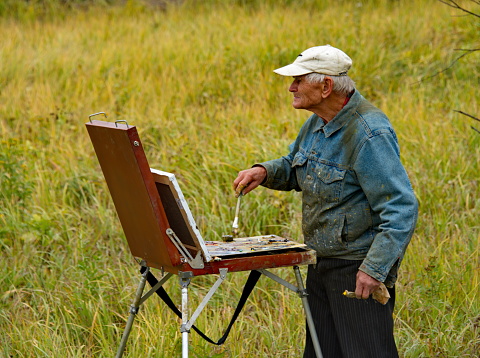 Istra. Russia. October 09, 2018. The famous Russian painter Anatoly Tikhonovich Selyutin paints a landscape with golden domes of the New Jerusalem Monastery with a special technique.