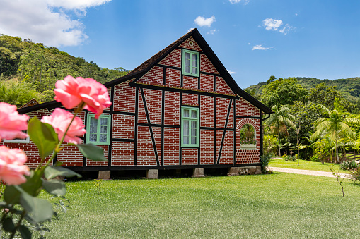 Pomerode, Santa Catarina, Brazil - December 26, 2021: A close-up view of the pink roses and a half-timbered building at the 'Rota do Enxaimel' in Pomerode, Santa Catarina state - Brazil
