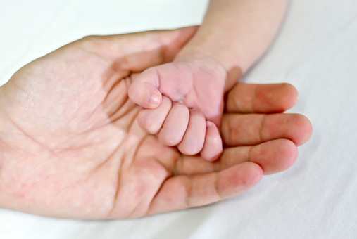 hands of a newborn baby with the nails, holding his mothers hand