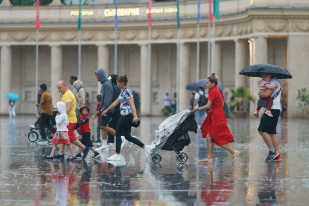 Wet people in rainy day in city center at summer. Moscow, Russia - July 10, 2022: Raining day in city center at summer. Wet people. Raincoat and umbrellas as protection. Texture of strong, fresh and powerful water drops and sprays. Tropical storm urgency mother working father stock pictures, royalty-free photos & images