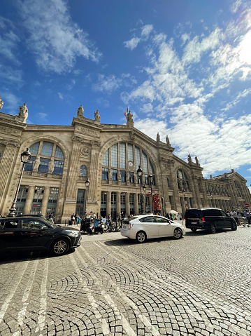 Paris, France -  10th June, 2022: People and traffic outside Gare du Nord railway station. The red Angel Bear statue in front of the entrance is by Richard Texier.