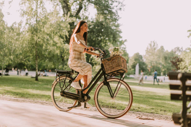 Young woman riding  electric bike with flowers in the basket stock photo