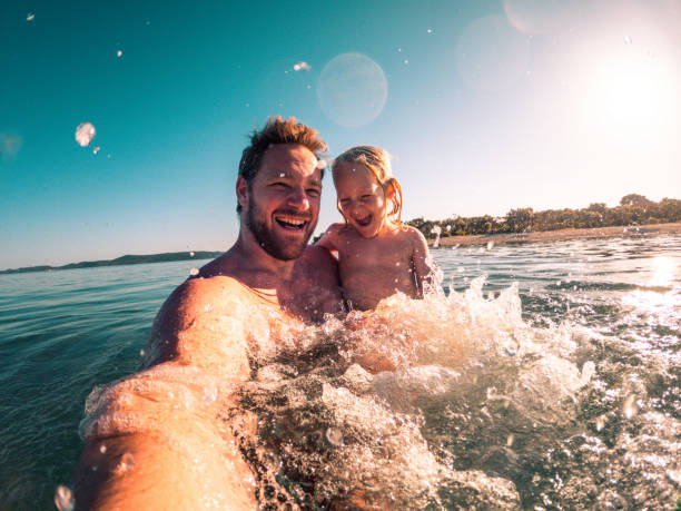 istock Sunset Fun, White Father and Son Taking a Selfie in the Sea 1410154159