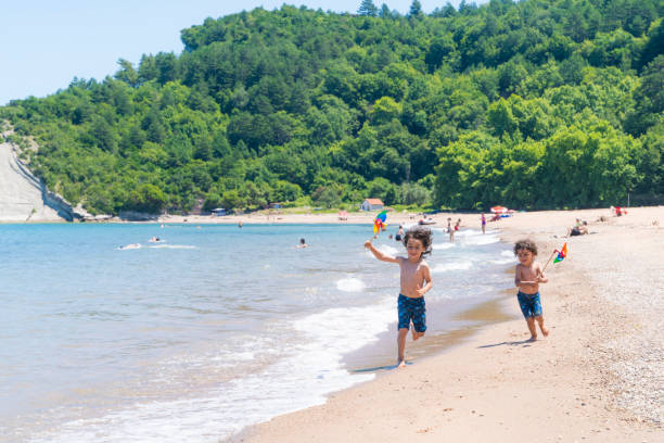 화려한 날씨 베인을 가진 소년들이 해변에서 달리고 있습니다. - turkey black sea coast 뉴스 사진 이미지