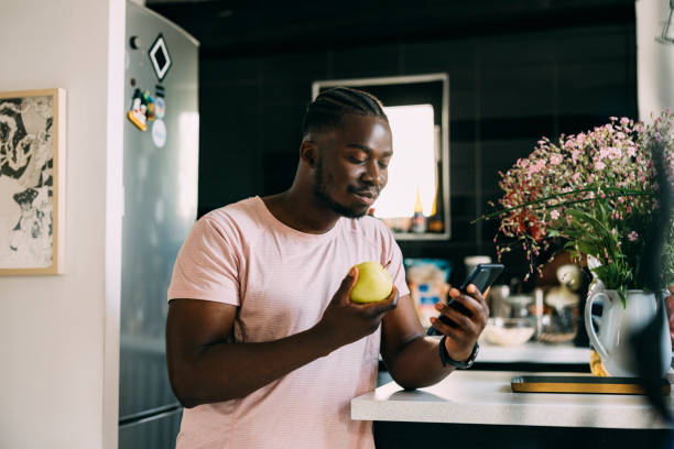 istock Afro-American Eating An Apple While Being On His Mobile Phone 1410159888
