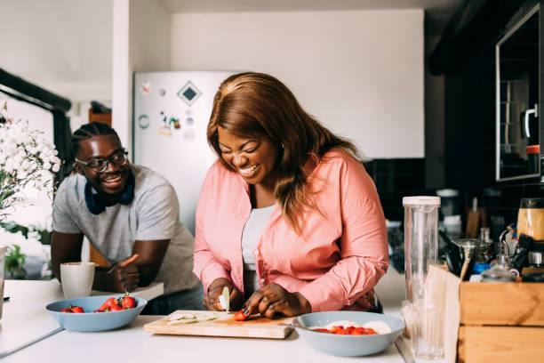 Couple Preparing Breakfast Together Afro-American couple preparing their meal together in the kitchen. body positive couple stock pictures, royalty-free photos & images