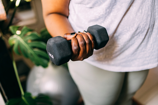 Close up shot of an anonymous woman holding a dumbbell.