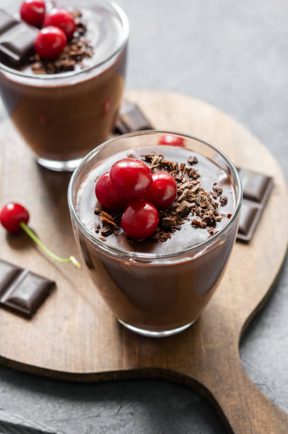 istock Chocolate cocoa pudding with sour cherry, mousse in glass cup on rustic table, supangle 1410160477