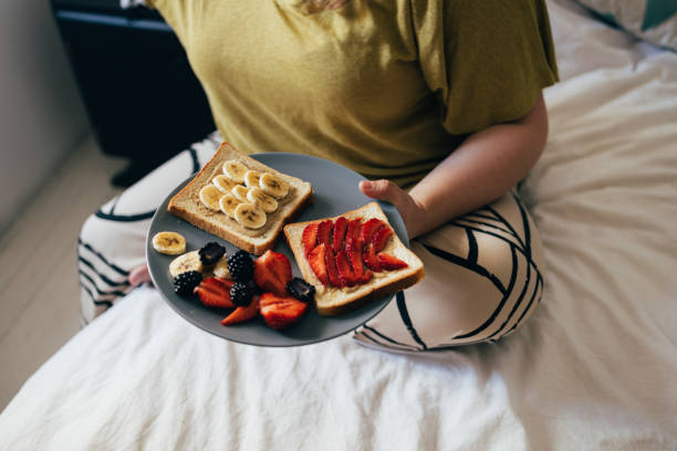 Anonymous woman holding a plate with her breakfast on it.