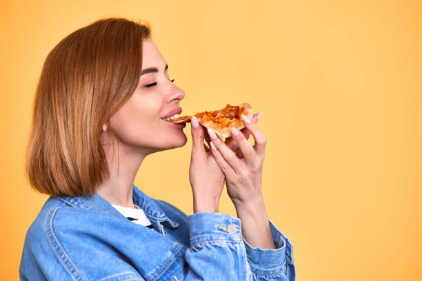 istock young woman eating pizza slice and looking delighted 1410161517