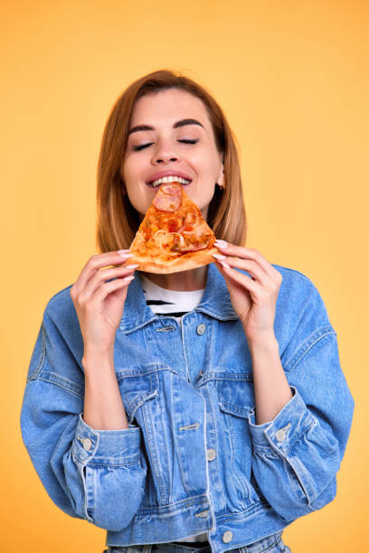 istock young woman eating pizza slice and looking delighted 1410161522