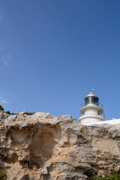 istock the top of a white lighthouse peeking over stone cliffs, Caballeria Lighthouse, Menorca, Balearic Islands 1410162585