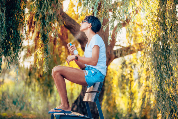 mujer disfrutando de sentarse al aire libre pero también rociando repelente de mosquitos en su piel expuesta - insect repellant mosquito bug bite spraying fotografías e imágenes de stock