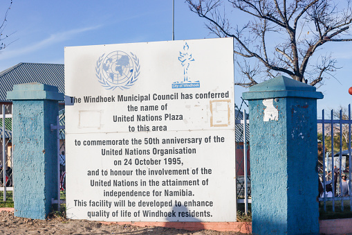 People can be seen at the background at United Nations Plaza at Katutura near Windhoek in Khomas Region, Namibia, with a sign indicating that the area was thus named due to UN involvement in Namibia's independence from South Africa and colonial Germany.