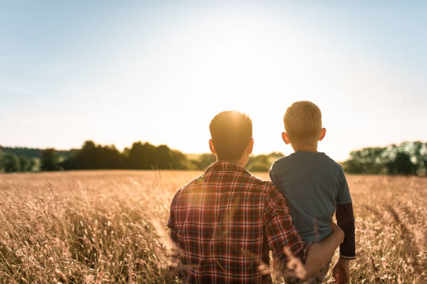 Father spending time with his child walking together in the park at sunset. stock photo