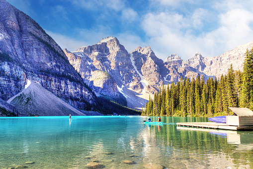 Visitors canoeing their boats on turquoise-colored Moraine Lake in the Canadian Rockies of Banff National Park near Lake Louise. The Valley of the Ten Peaks in the background.