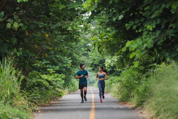 eles são um casal asiático correndo e se exercitando. - couple stretching running jogging - fotografias e filmes do acervo