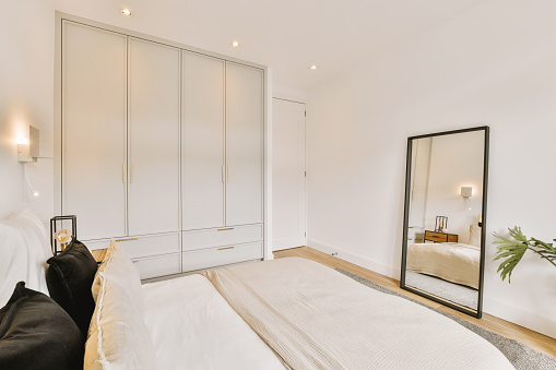 Interior of a bedroom with a large bed located next to a wardrobe in a minimalist style in a modern apartment