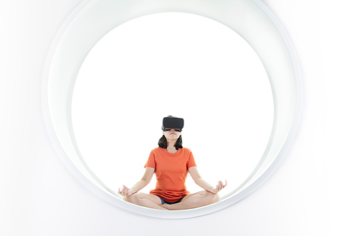 Women wearing virtual reality goggle glasses online metaverse technology. Relax with yoga traning at home modern interior.