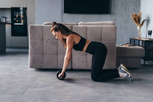 istock Fit woman working out with ab exercise wheel at home. 1410177453