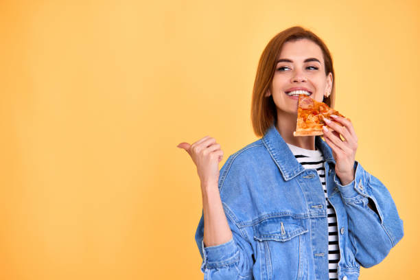 istock young woman eating pizza slice and looking delighted 1410178091