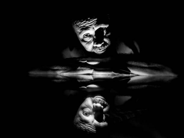istock Black and white closeup of man face lying on glass with reflection. 1410180238