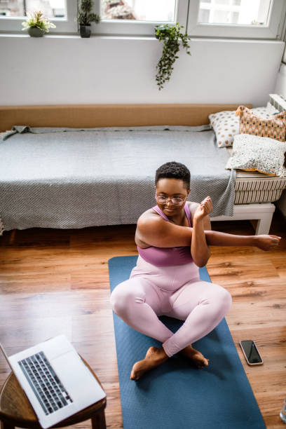 istock Woman working out at home while watching online yoga class. 1410180912