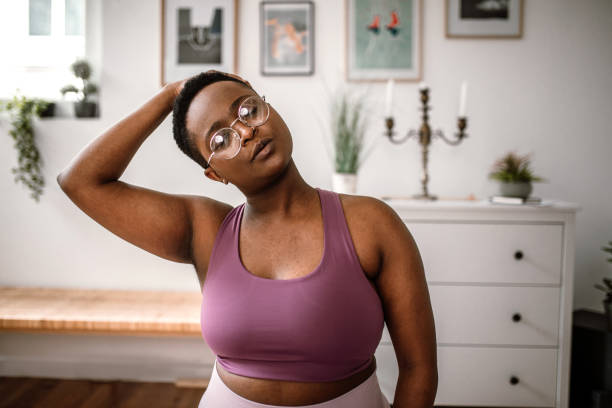istock Young woman doing neck stretching exercises at home 1410180967