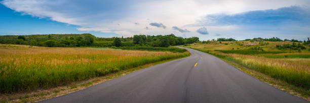 le paysage spectaculaire avec la route sinueuse à travers la prairie dorée et verte au big stone national wildlife refuge à minnesota river, odessa, minnesota - country road photos et images de collection