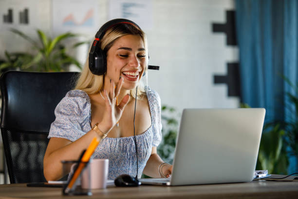 istock Young female entrepreneur waving at laptop webcam during a video conference call 1410194468