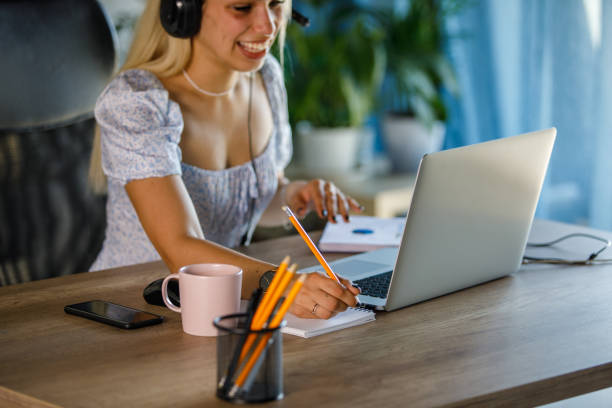 istock Young woman writing notes while video chatting with a business colleague 1410194469