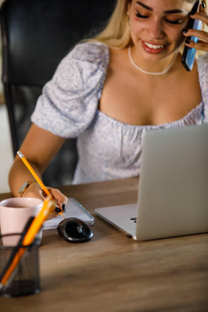 istock Young woman taking notes during a conference call with a business partner 1410194518