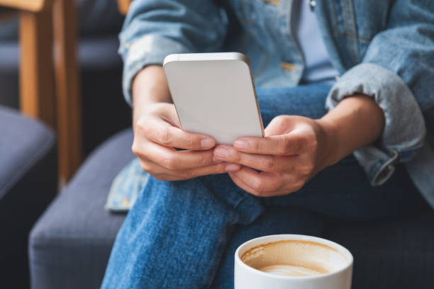 istock Closeup image of a woman holding and using mobile phone with coffee cup on the table 1410196825