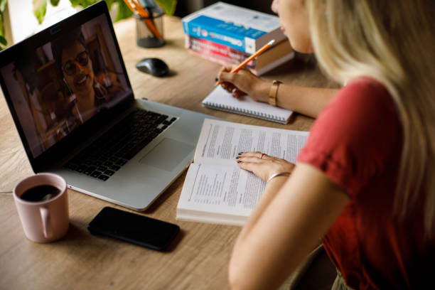 istock Young woman writing notes while studying for a test with a friend on a video call 1410196985