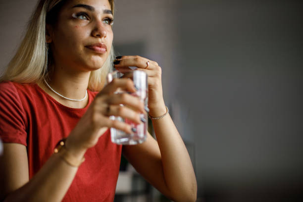 istock Young woman looking away and contemplating while taking her medication 1410198068