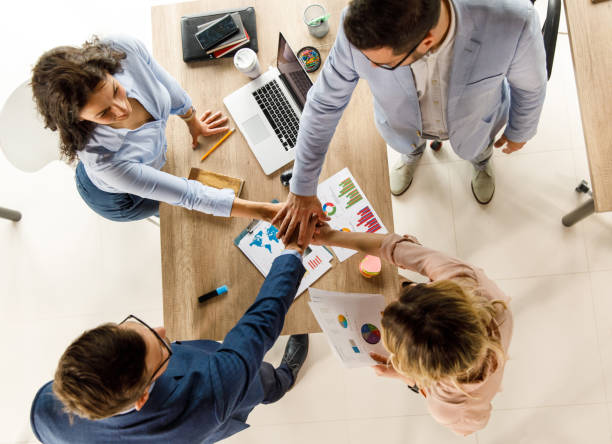istock Four business colleagues joining their hands over a conference table after a successful meeting 1410198190