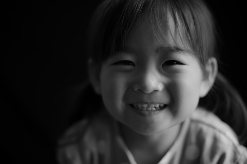 A little pretty toddler girl with blue eyes looking up seriously by the window with her eyebrows up