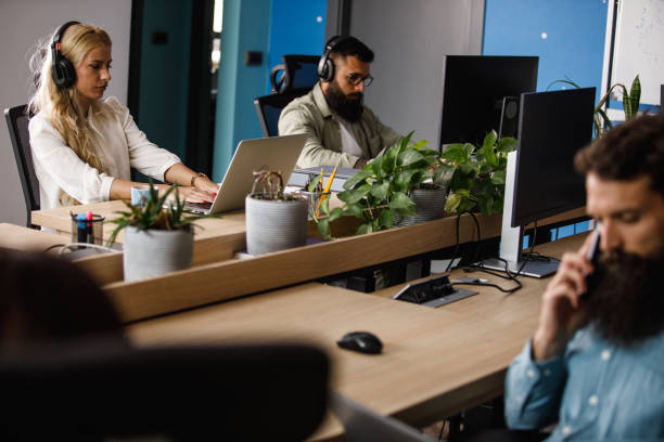 istock Two computer programmers sitting at their desks, wearing headphones, diligently working 1410200498