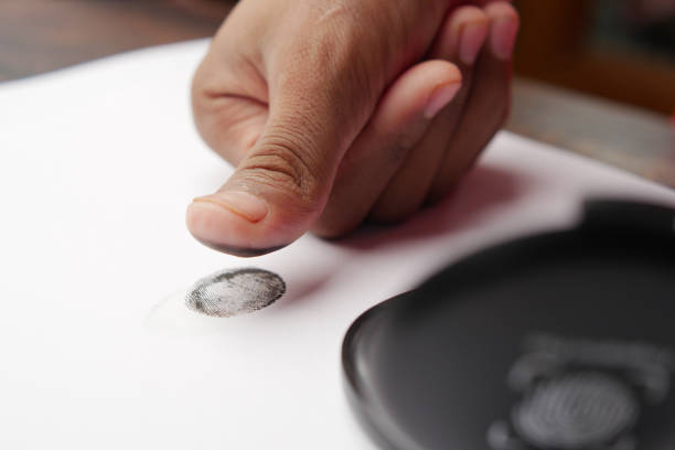 person hand putting black fingerprints on a paper close up