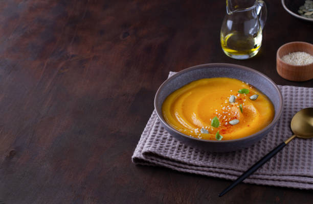 istock Pumpkin soup in a plate on a wooden table, copy space 1410201487