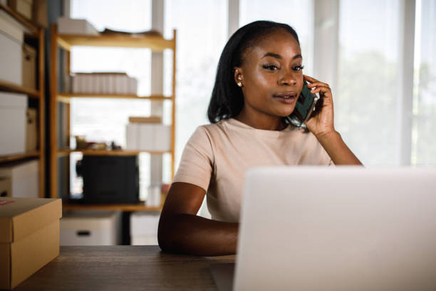 istock Young businesswoman checking data on laptop while talking on the phone with a client 1410201856