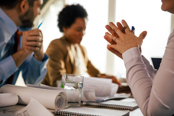 istock Woman sitting with hands clasped, listening to her colleagues share ideas during a project meeting 1410202894