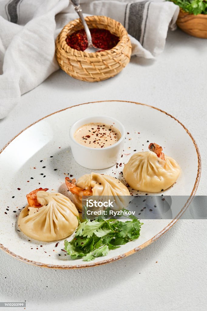 Steamed dumplings shrimp in asian style on white concrete background. Prawn dim sum with sauce on ceramic plate. Shrimp wontons on dish in minimal style. Asian dumplings with seafood. Steamed dumplings shrimp in asian style on white concrete background. Prawn dim sum with sauce on ceramic plate. Shrimp wontons on dish in minimal style. Asian dumplings with seafood Jiaozi Stock Photo