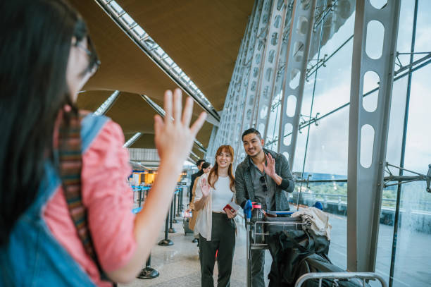 bienvenidos de nuevo, mamá y papá. feliz joven asiática china saludando de la mano saludando a su mamá y papá en la sala de llegadas del aeropuerto, - separation airport child waving fotografías e imágenes de stock