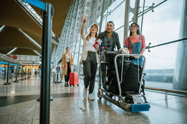 Asian family with luggage on trolley at airport stock photo