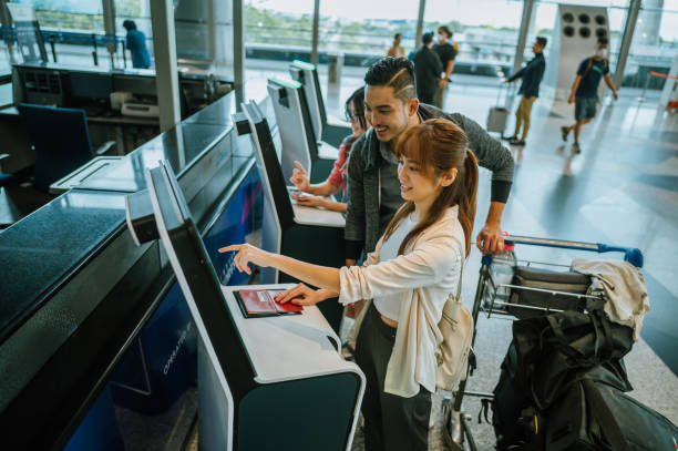 Asian couple using automated check-in kiosk in airport Shot of Asian Chinese couple using touch screen display to confirm identity in airport terminal, travel, technology, klia airport stock pictures, royalty-free photos & images